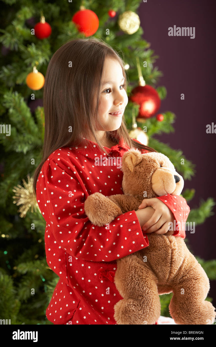 Young Girl Cuddling Teddy Bear In Front Of Christmas Tree Stock Photo ...