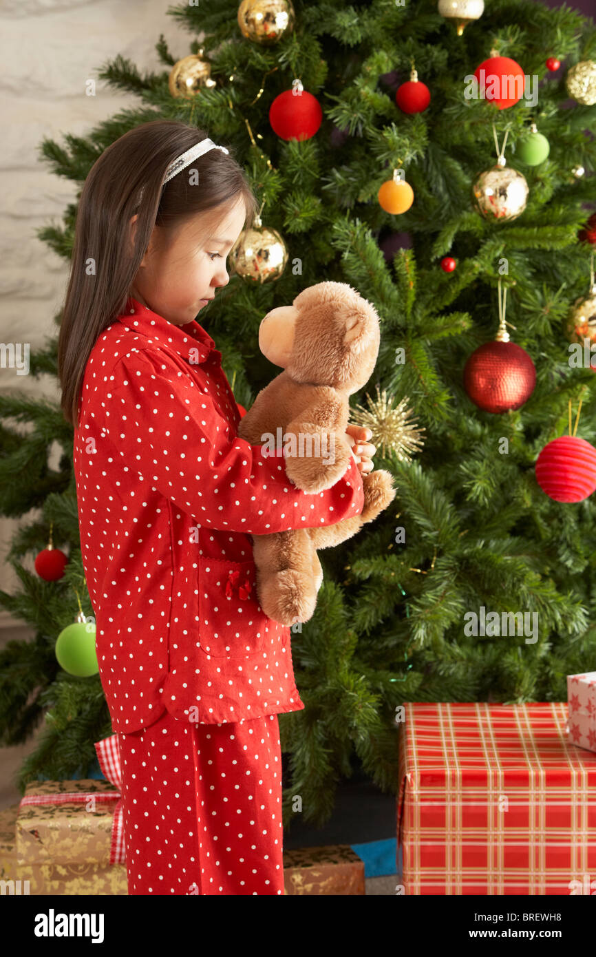 Young Girl Cuddling Teddy Bear In Front Of Christmas Tree Stock Photo ...