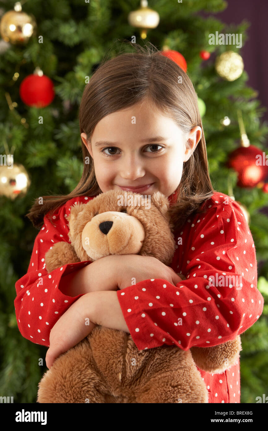 Young Girl Cuddling Teddy Bear In Front Of Christmas Tree Stock Photo ...