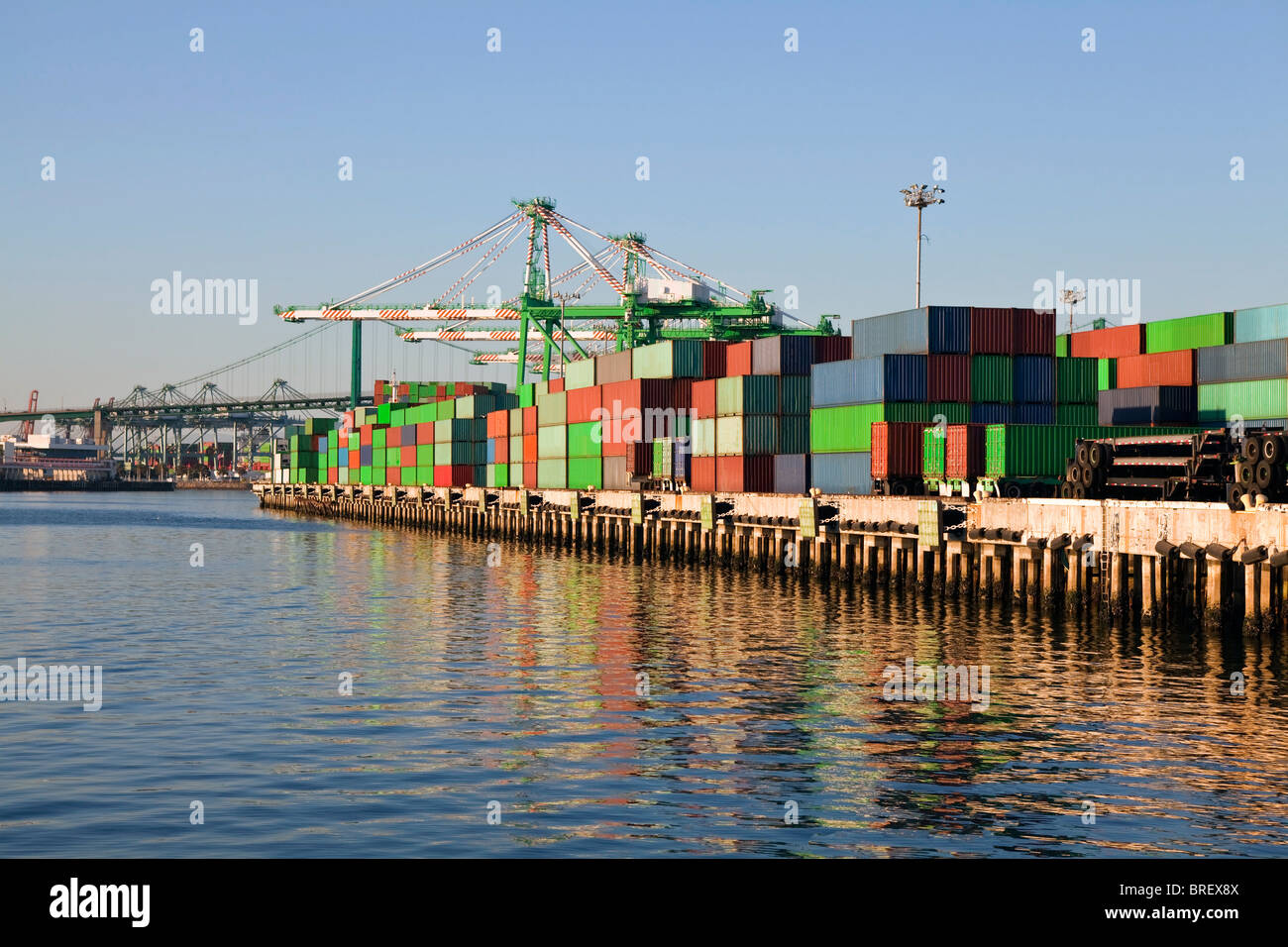 Shipping containers and harbor cranes in warm late afternoon light. Stock Photo