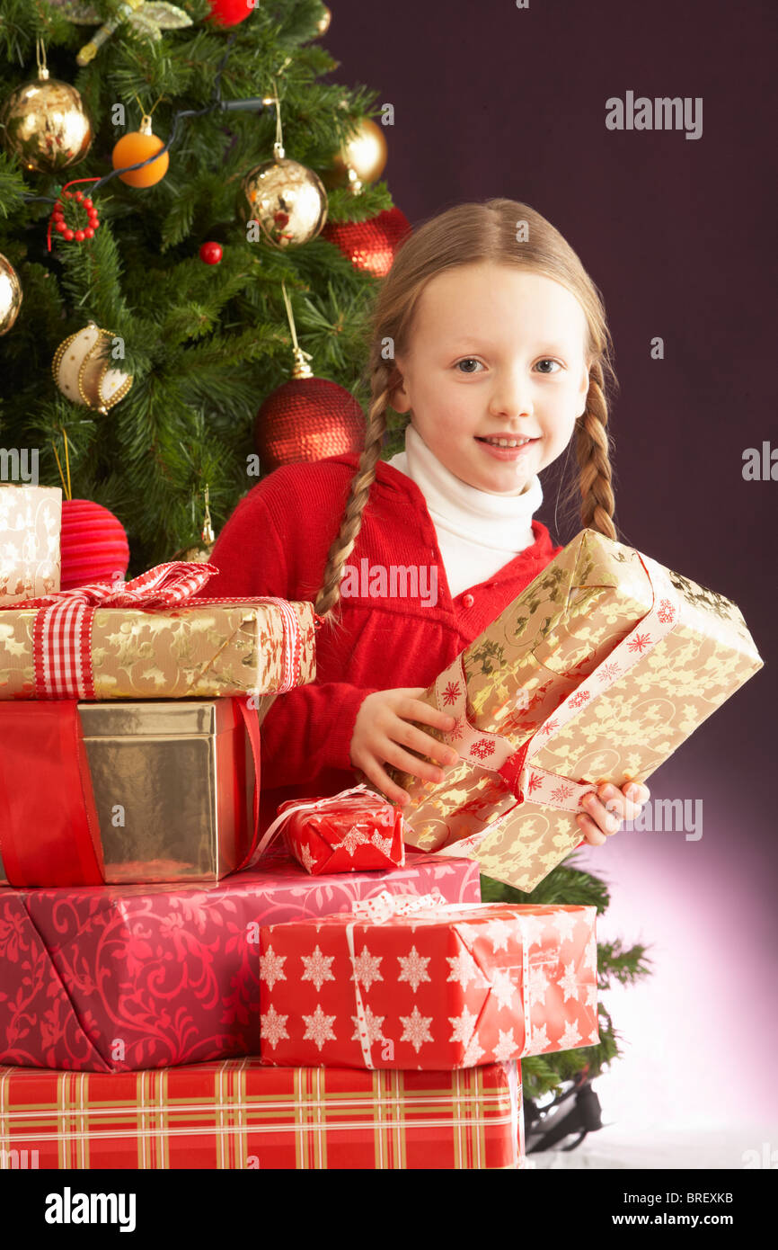 Young Girl Holding Christmas Present In Front Of Christmas Tree Stock ...