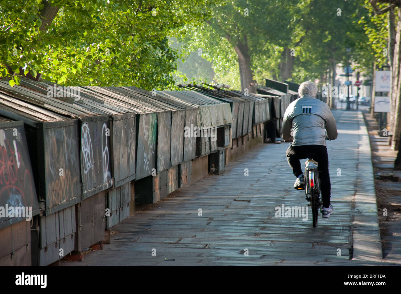 A man rides a bicycle along the Seine in Paris, France Stock Photo