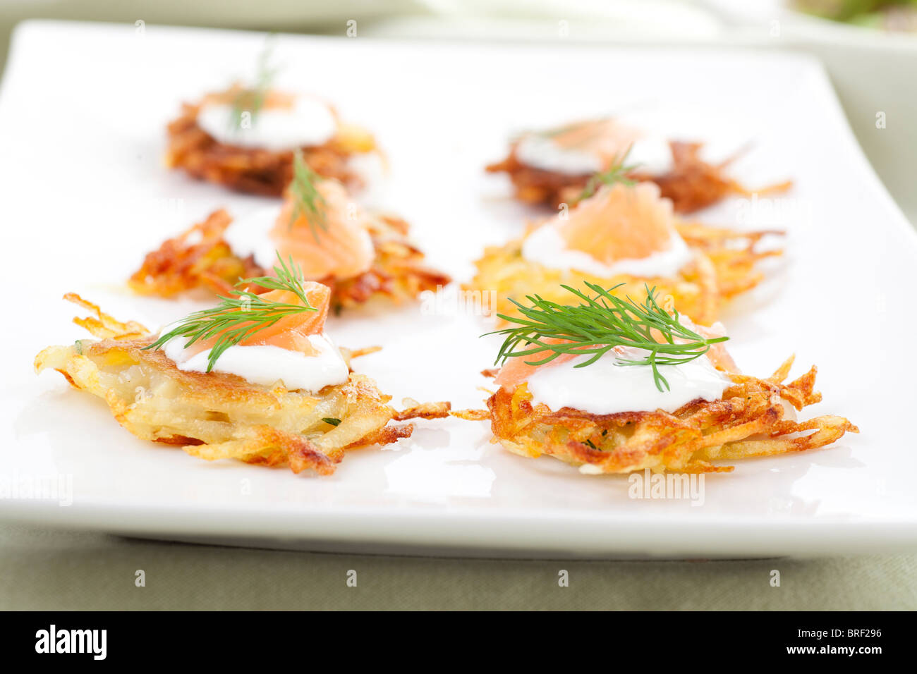 Bite sized potato rosti appetizer topped with fresh sour cream, smoked ...