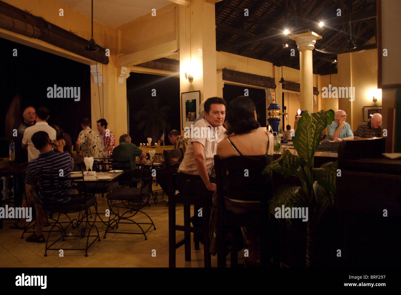 People are gathered inside The Foreign Correspondents Club (FCC) to enjoy food and drink in Phnom Penh, Cambodia. Stock Photo