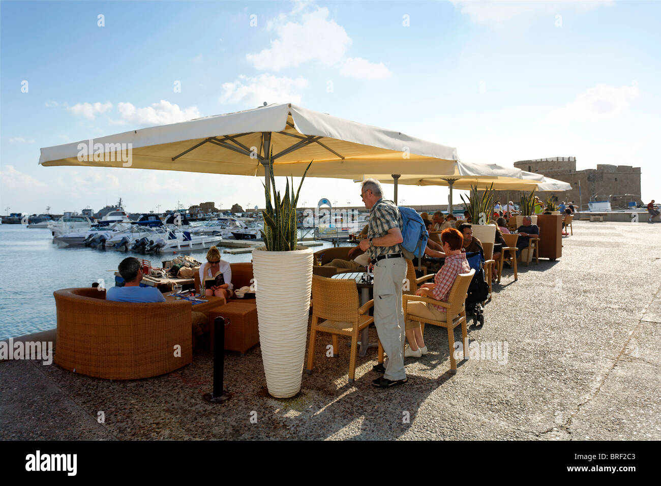 People in a cafe with sun umbrellas at the shore promenade, citadel, Paphos, Pafos, Cyprus, Europe Stock Photo