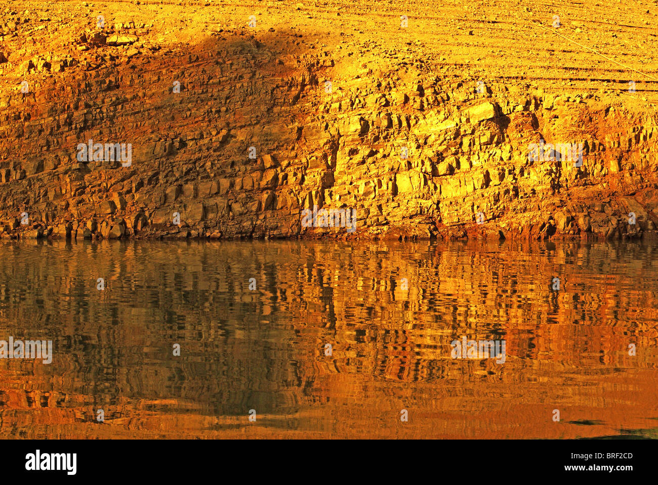 Reflection of rock shoreline on water on Lake Shasta Stock Photo