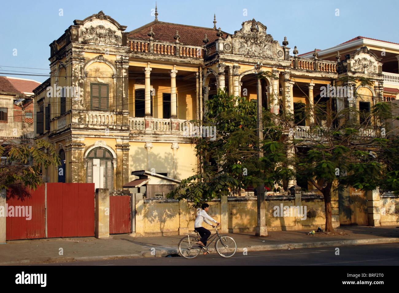 The architectural influence of French colonialism on Phnom Penh's city center area can be viewed by a passing bicyclist. Stock Photo