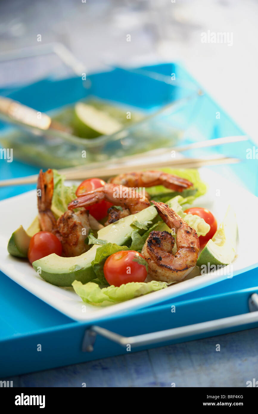 Grilled chilli prawns, lettuce and avocado salad with lime-cumin dressing on a blue serving tray Stock Photo
