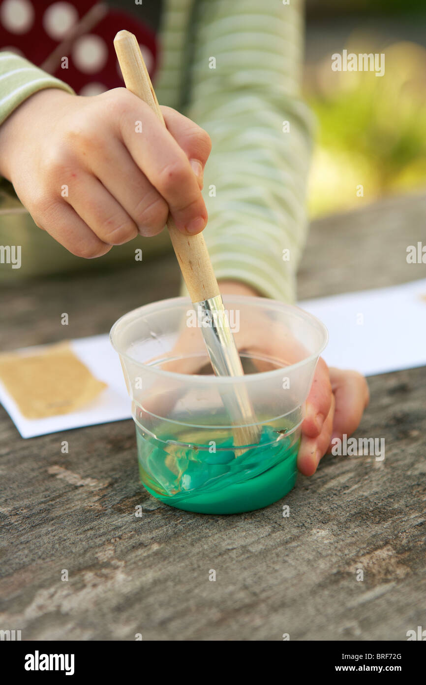 Girl mixing green paint with brush in a pot Stock Photo Alamy