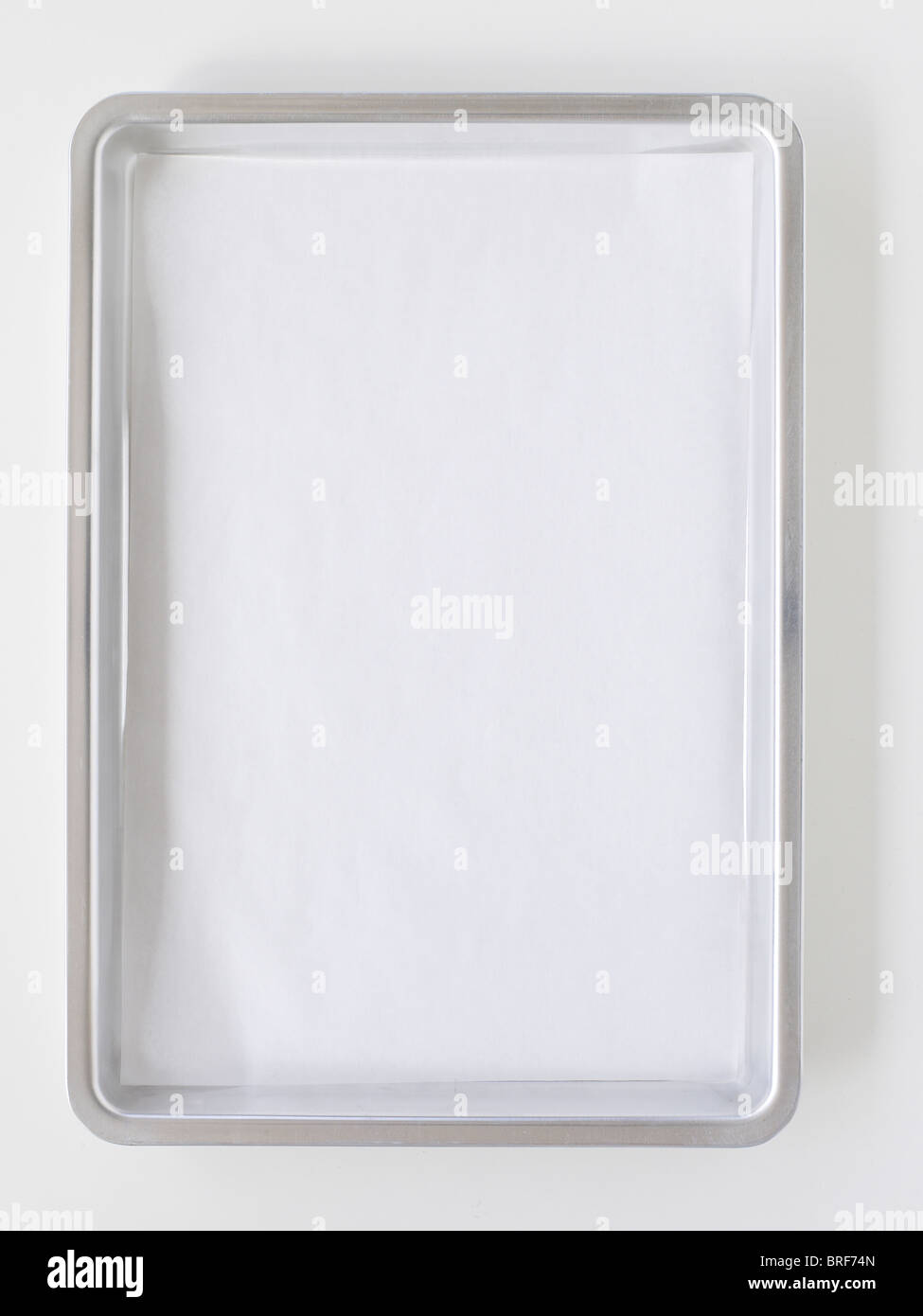 Baking sheet lined with greaseproof baking parchment on white