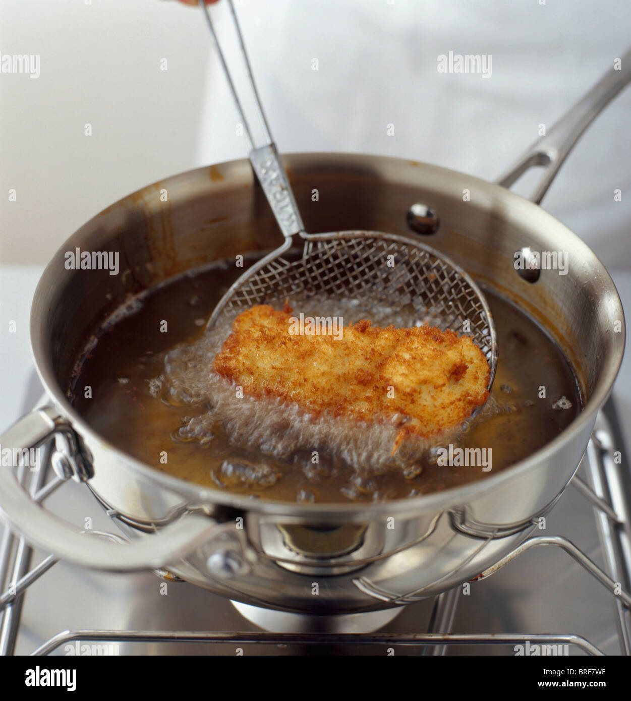 Deep frying chicken in shallow pan of oil Stock Photo Alamy