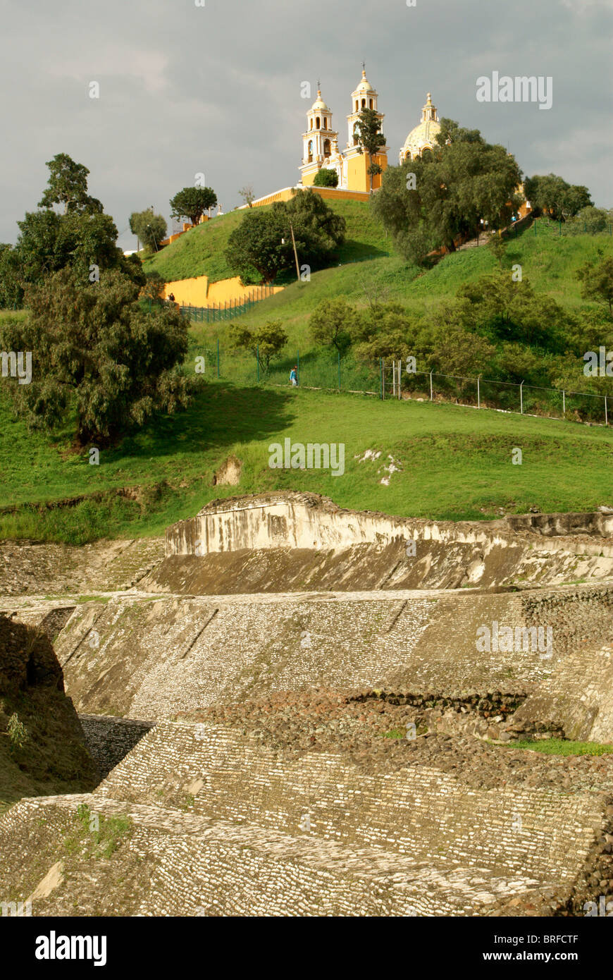 Pre-Hispanic ruins at base of Tepanapa Pyramid and Santuario de Nuestra Senora de los Remedios church in Cholula, Puebla, Mexico Stock Photo