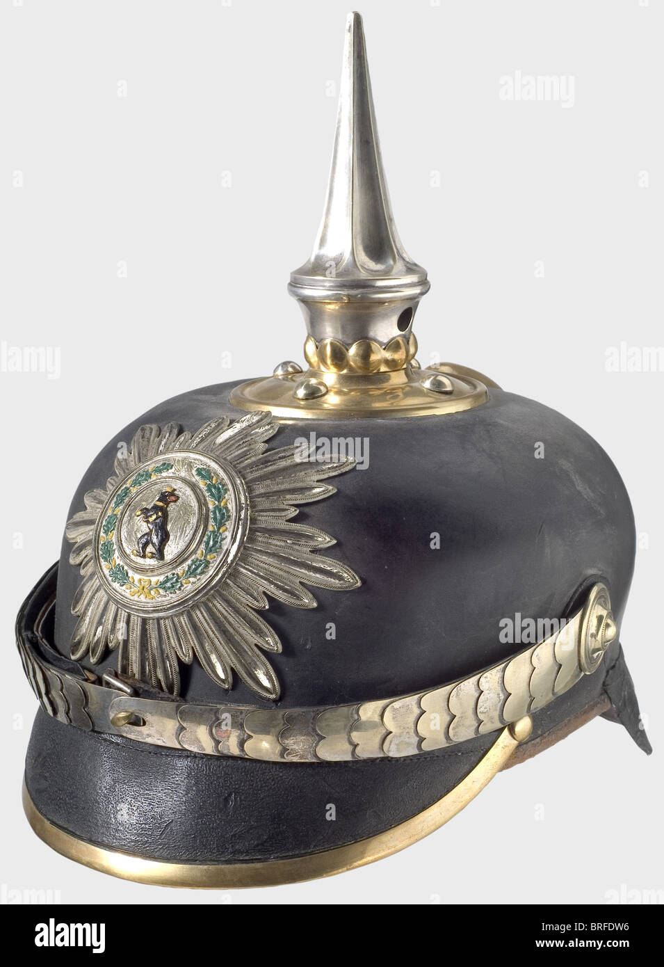 A helmet with unknown attribution., Leather skull with brass front and rear peak edging, round top plate, also of brass with a bead and reel frieze and round-headed screws. Silver-plated, fluted spike, metal chinscales, and a star emblem. On the silver medallion a rampant heraldic bear within a colour painted oak leaf wreath. Brown ribbed silk lining. Maker's label. Size 56. A fruitless search has already been made for the identification of a similar helmet in 1976/77 in the Orden Militaria Journal 17, 18, and 19. It may possibly be a police helmet. historic, h, Stock Photo