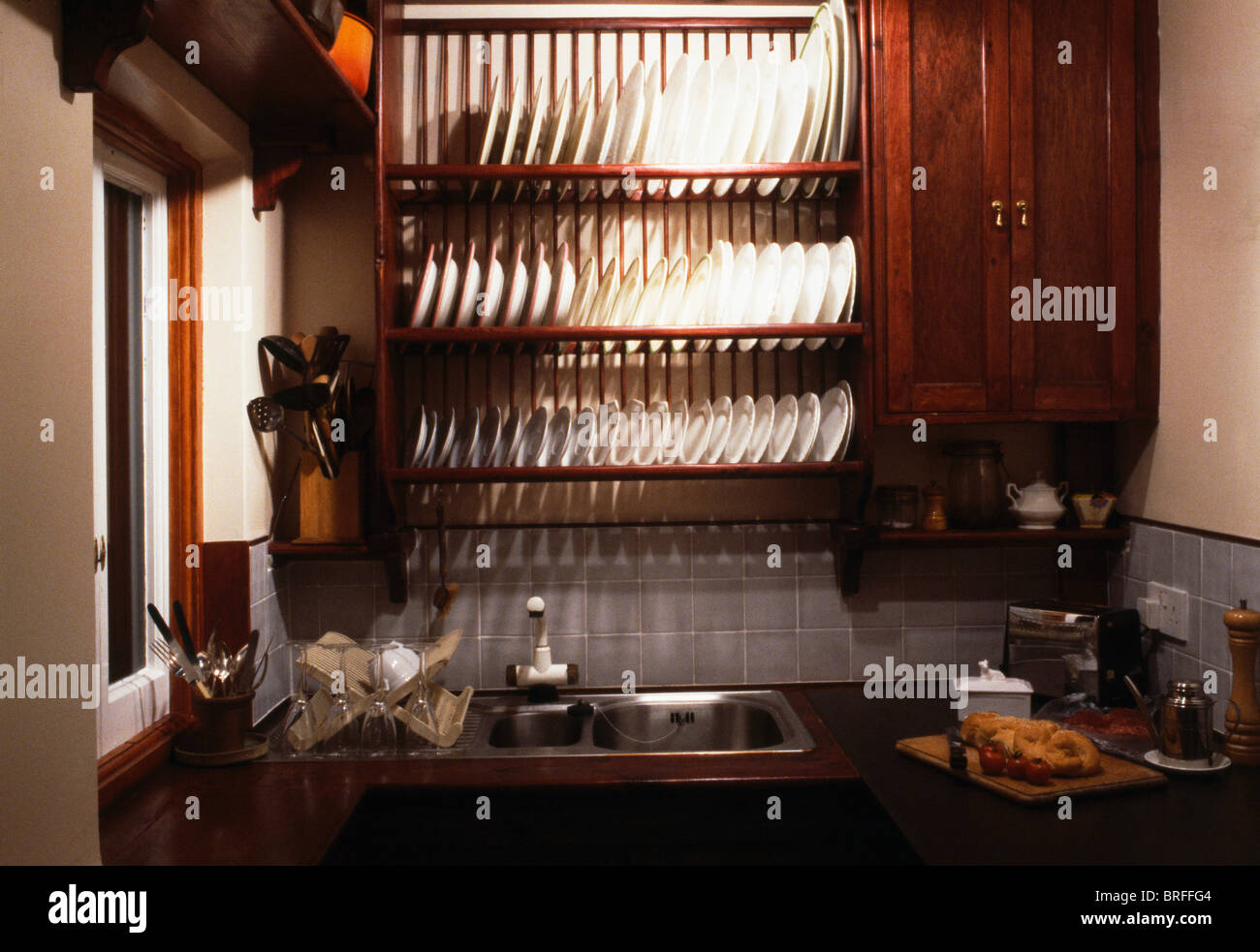 Closeup of white plates on storage rack above stainlesssteel sink in