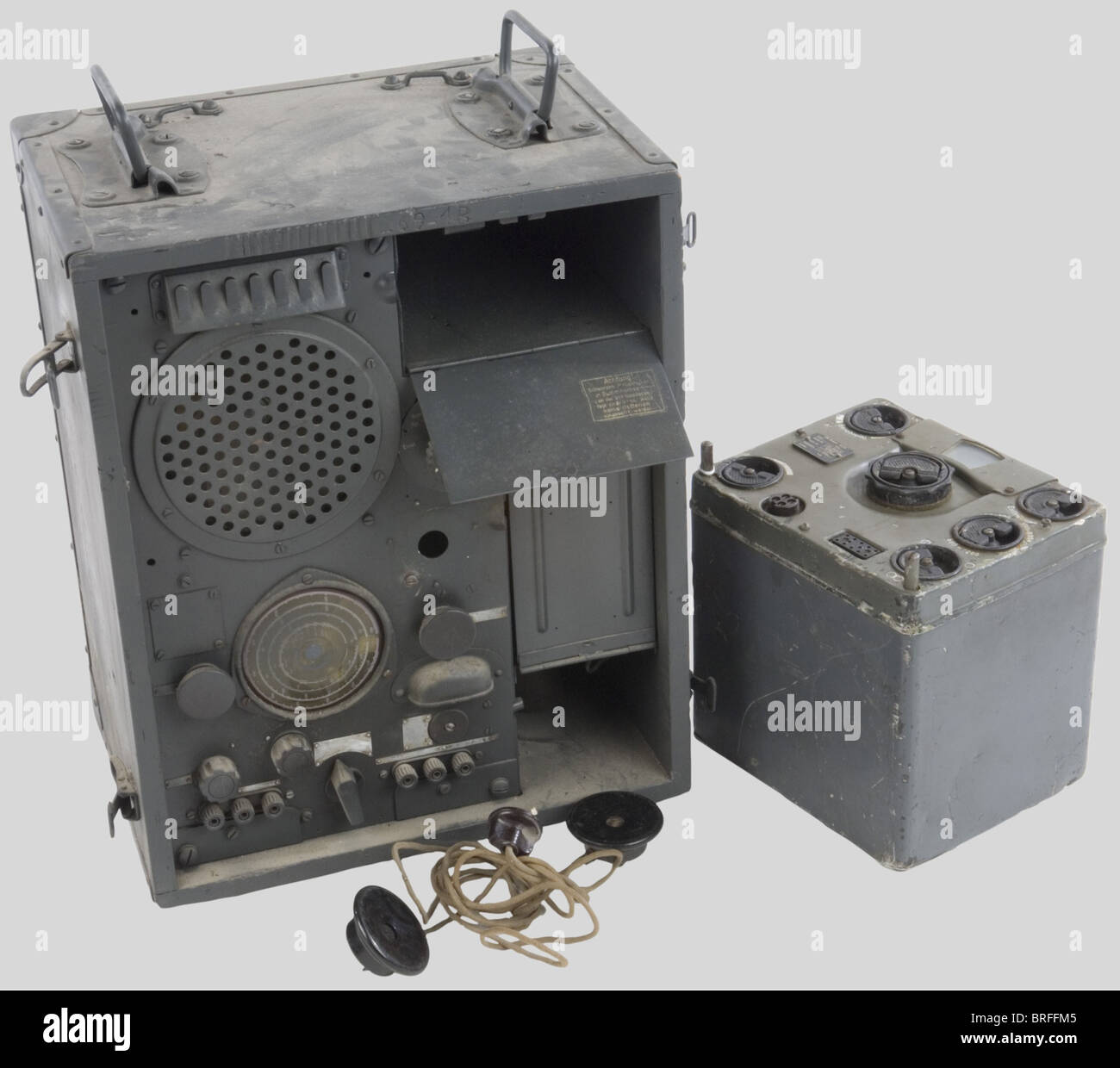 Two German army radio sets., One in a light grey wooden box, with all dials  and switches, the lid missing, with earphones, pretty used condition. The  other is square-shaped and of metal,