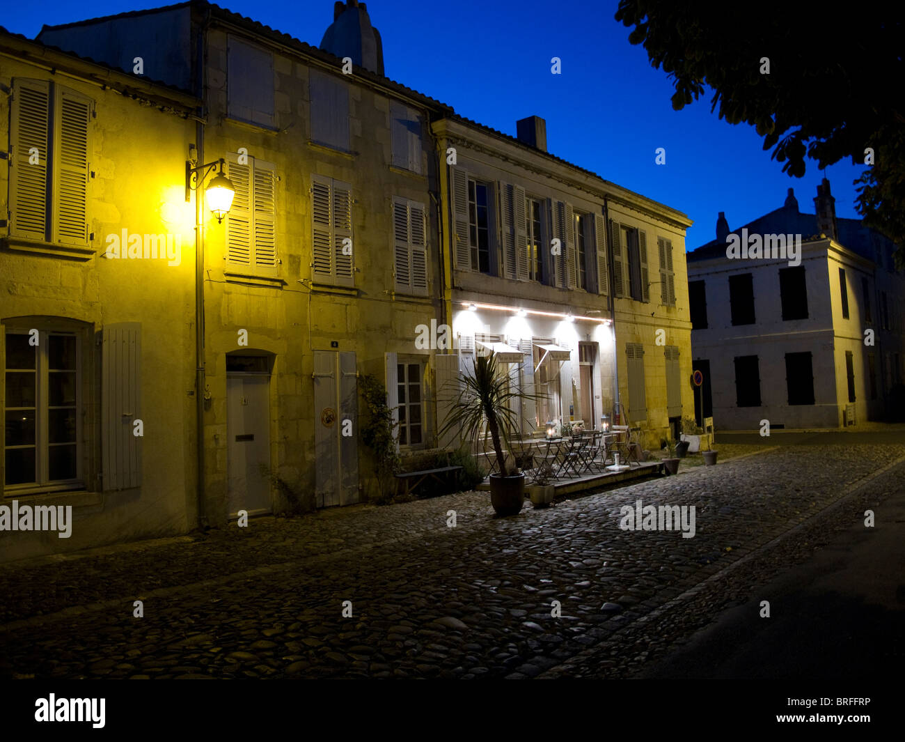 A restaurant at night under a clear sky and lit by street lights in the French town of St Martin de Re on the Ile de Re Stock Photo