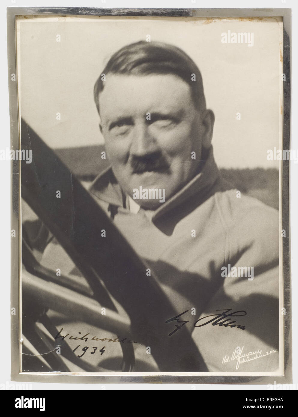 Adolf Hitler - autograph signature and date,in thick,black ink 'Weihnachten 1934 Adolf Hitler'(Christmas 1934 Adolf Hitler)on a large format Hoffmann photograph of Hitler in an overcoat sitting in the passenger's seat of an Mercedes convertible. The photographer's signature on the lower rim,'H. Hoffmann,München 2.N.W.' and the Hoffmann stamp on the back. Glued to the back piece of a simple,damaged(glass missing)tabletop frame. From the legacy of a high official of Daimler-Benz. historic,historical,people,1930s,20th century,NS,National Socialism,,Additional-Rights-Clearences-Not Available Stock Photo