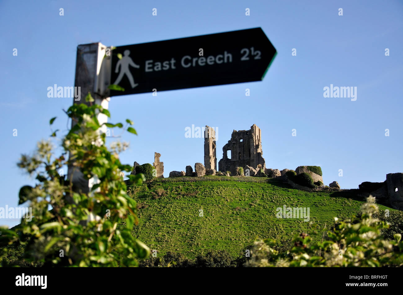 Ruins of Corfe Castle at sunset and walking trail sign, Corfe Castle, Isle of Purbeck, Dorset, England, United Kingdom Stock Photo