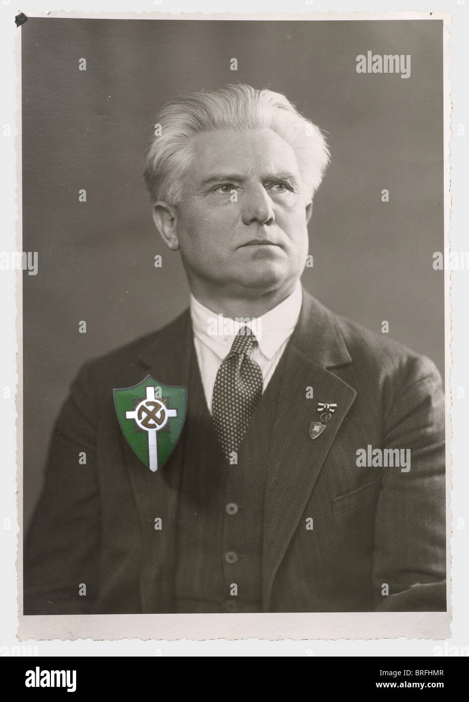Artur Dinter - German People's Church, photos, badges, documents, and newspapers. Green-white enamelled personal badge of the German People's Church, with portrait picture of Dinter wearing the badge on his lapel. 15 portrait photos with ink signatures of the leading figures of the German People's Church, conjoined on passepartout, framed, 50 x 40 cm. Two files with hardback editions of the journal 'Die religiöse Revolution - Kampfblatt der deutschen Volkskirche E.V. - Kampfbund', Vol. 1/1934 till Vol. 4/1937. Also documents and correspondence dealing with the , Stock Photo