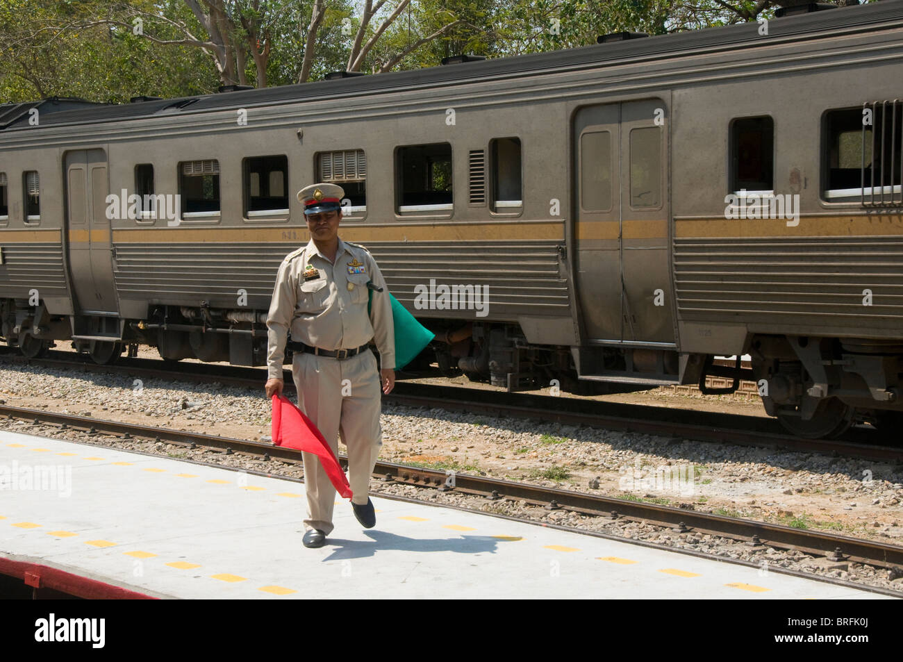 station master flagging a train at the railway station in Hua Hin Thailand Stock Photo