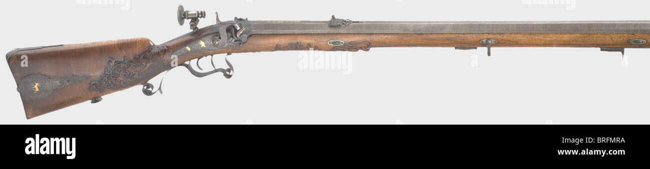 A percussion rifle,W. Edel,Leipzig,circa 1840. Octagonal Damascus barrel with patent breechblock and smooth bore in 8.5 mm calibre. Dovetailed globe front sight and adjustable rear sight. The signature,'A.W. EDEL IN LEIPZIG' is inlaid in gold(missing in places)on the chamber. Back action lock with a double snail,a folding buffer,and gold inlays of hunting themes on the lock plate and side plate. Hair trigger and adjustable aperture sight. Lavishly carved walnut full stock with bone nose cap(front ramrod thimble loose). Patch box lid,trigger guard,and,Additional-Rights-Clearences-Not Available Stock Photo