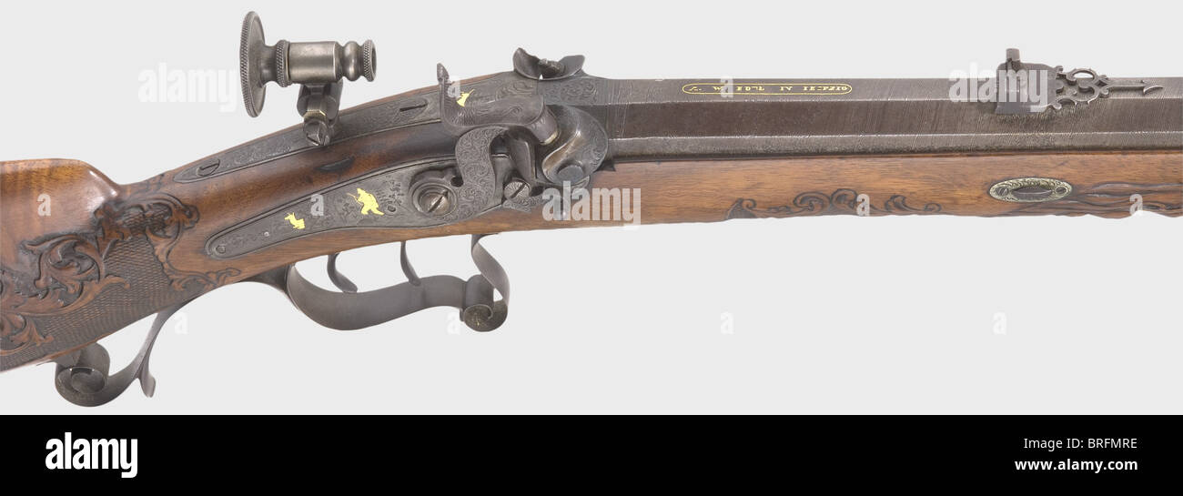 A percussion rifle,W. Edel,Leipzig,circa 1840. Octagonal Damascus barrel with patent breechblock and smooth bore in 8.5 mm calibre. Dovetailed globe front sight and adjustable rear sight. The signature,'A.W. EDEL IN LEIPZIG' is inlaid in gold(missing in places)on the chamber. Back action lock with a double snail,a folding buffer,and gold inlays of hunting themes on the lock plate and side plate. Hair trigger and adjustable aperture sight. Lavishly carved walnut full stock with bone nose cap(front ramrod thimble loose). Patch box lid,trigger guard,and,Additional-Rights-Clearences-Not Available Stock Photo
