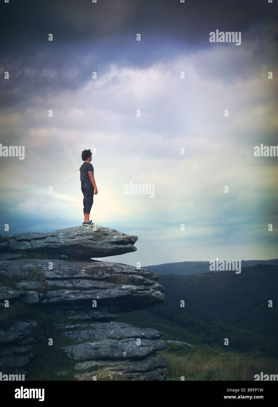 boy stood on rocks looking across moors Stock Photo