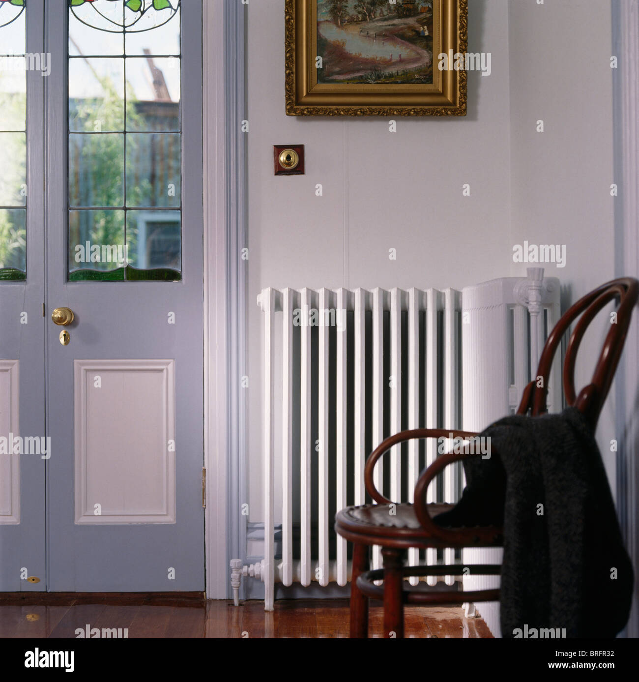 Antique bentwood chair beside white radiator in traditional hall with ...
