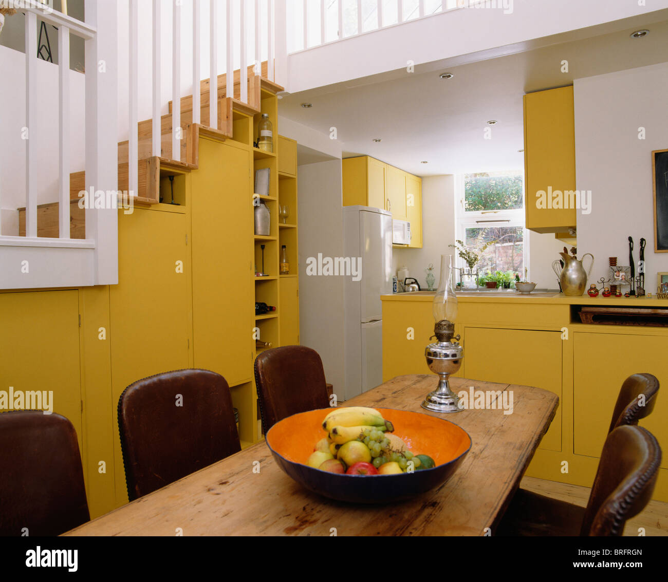Bowl of fruit on old pine table in modern openplan yellow kitchen