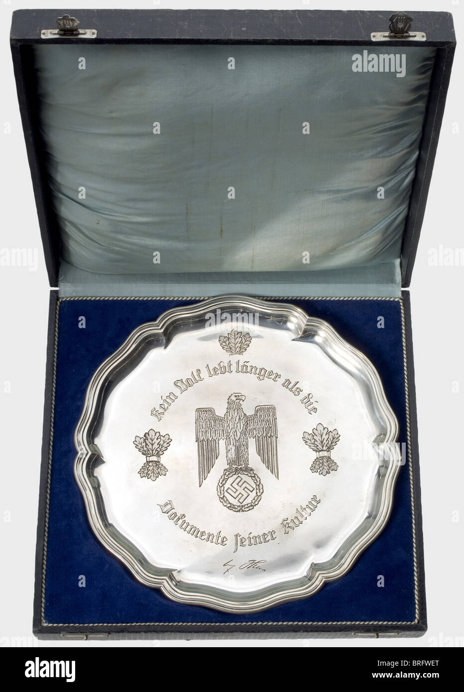 A silver presentation bowl.,Rose-bordered plate with the heraldic eagle,oak leaf bundles,and the inscription,'Kein Volk lebt länger als die Dokumente seiner Kultur'(No people lives longer than the documents of its culture)along with a facsimile signature of Adolf Hitler engraved in the centre. The silversmith's mark 'Wellner' and the hallmark '800' on the back. Weight 521 g. Diameter 30 cm. It comes with the certificate awarding the title of professor(envelope with punch-holes)to the Senior Administrative Councilor,Dr. Berthold Widmann,Reich's Commiss,Additional-Rights-Clearences-Not Available Stock Photo