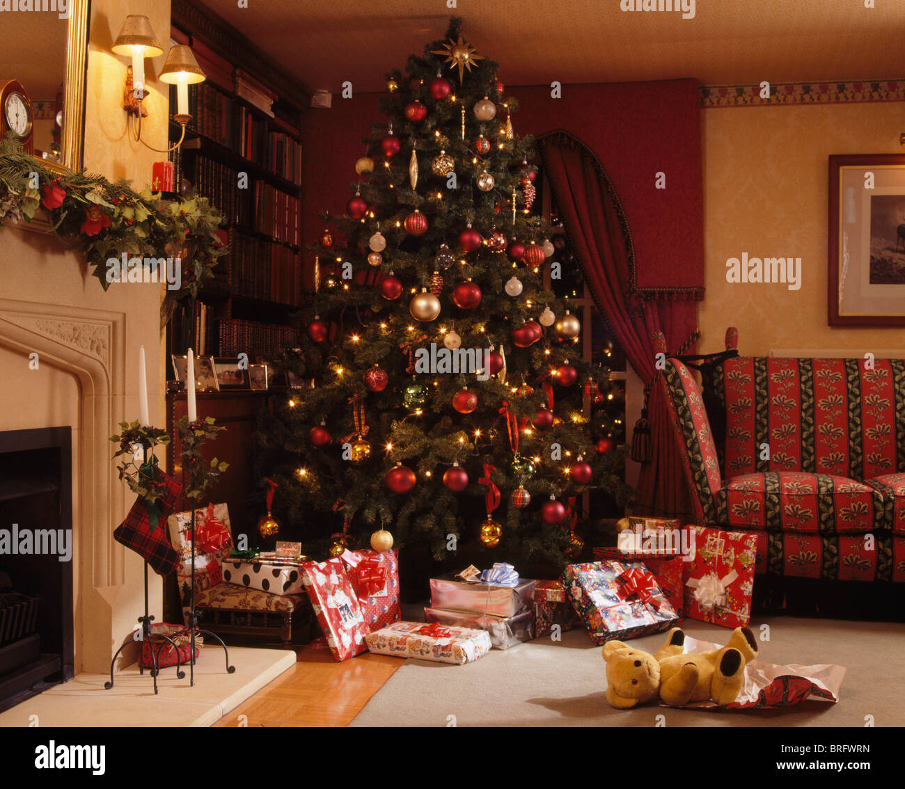 Wrapped gifts below tall decorated Christmas tree in corner of