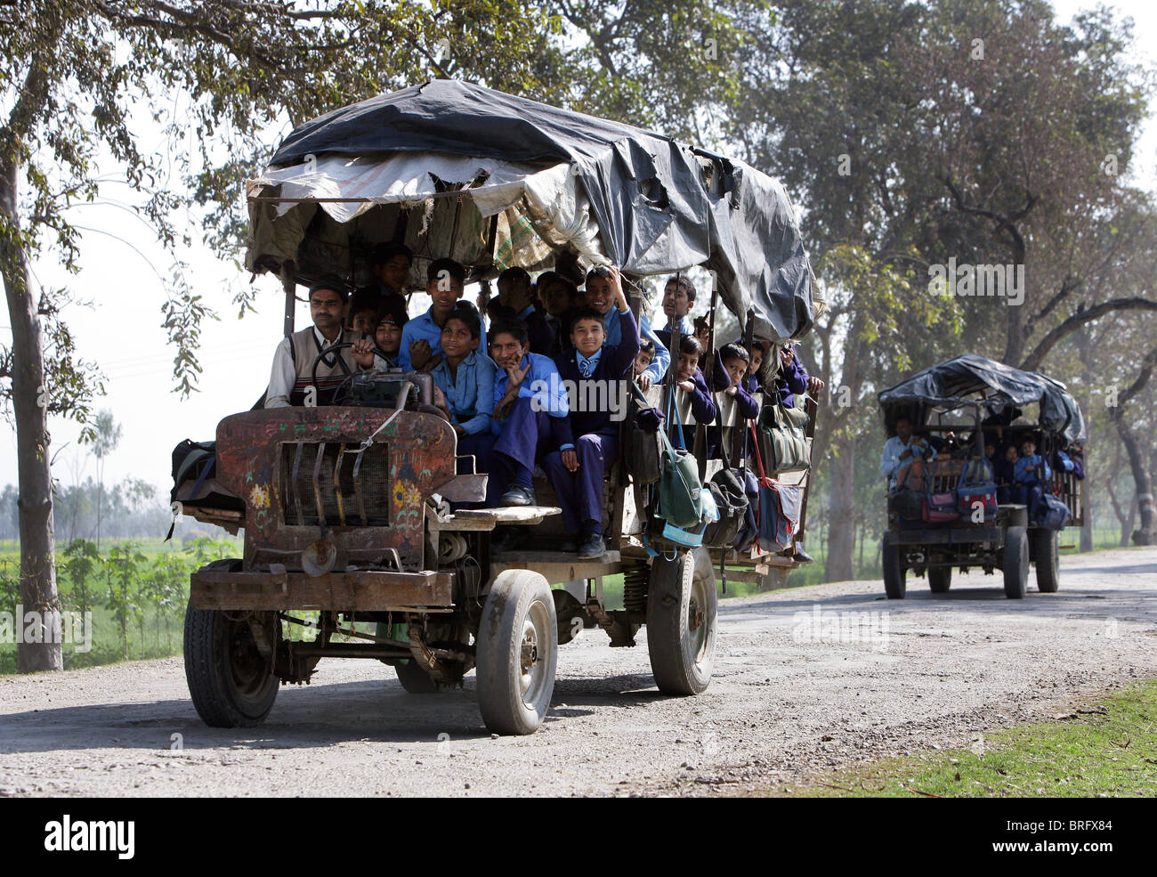 Schoolchildren riding home from school using an old tractor. Uttar Pradesh, India Stock Photo