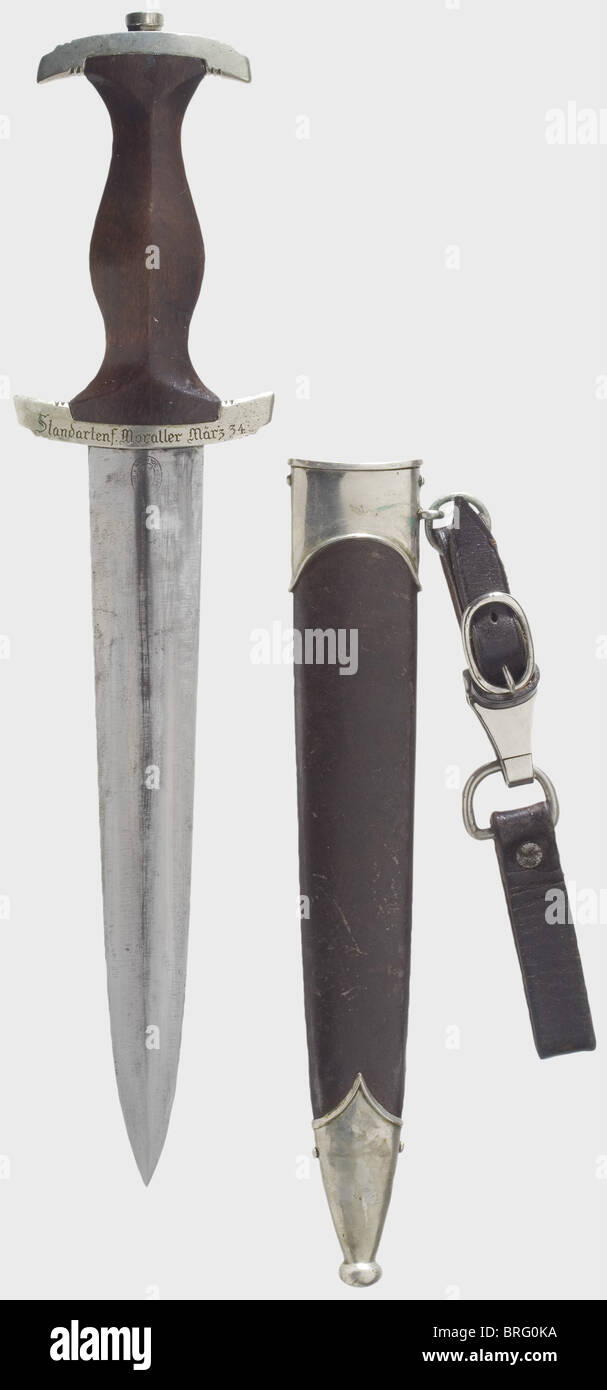 A model 33 service dagger.,Blade with etched motto. Reverse side shows traces of grinding from the removal of the Röhm dedication,early maker's logo 'Eickhorn/Solingen'. Brown wooden grip. Nickle quillons,the lower one engraved on the reverse side with,'Standartenf. Moraller März 34'. Browned iron scabbard with nickel mountings. Leather suspension strap. Length 35 cm. Cleaned and varnished. historic,historical,1930s,1930s,20th century,storm battalion,stormtroopers,armed and uniformed branch of the NSDAP,organisation,organization,organizations,org,Additional-Rights-Clearences-Not Available Stock Photo