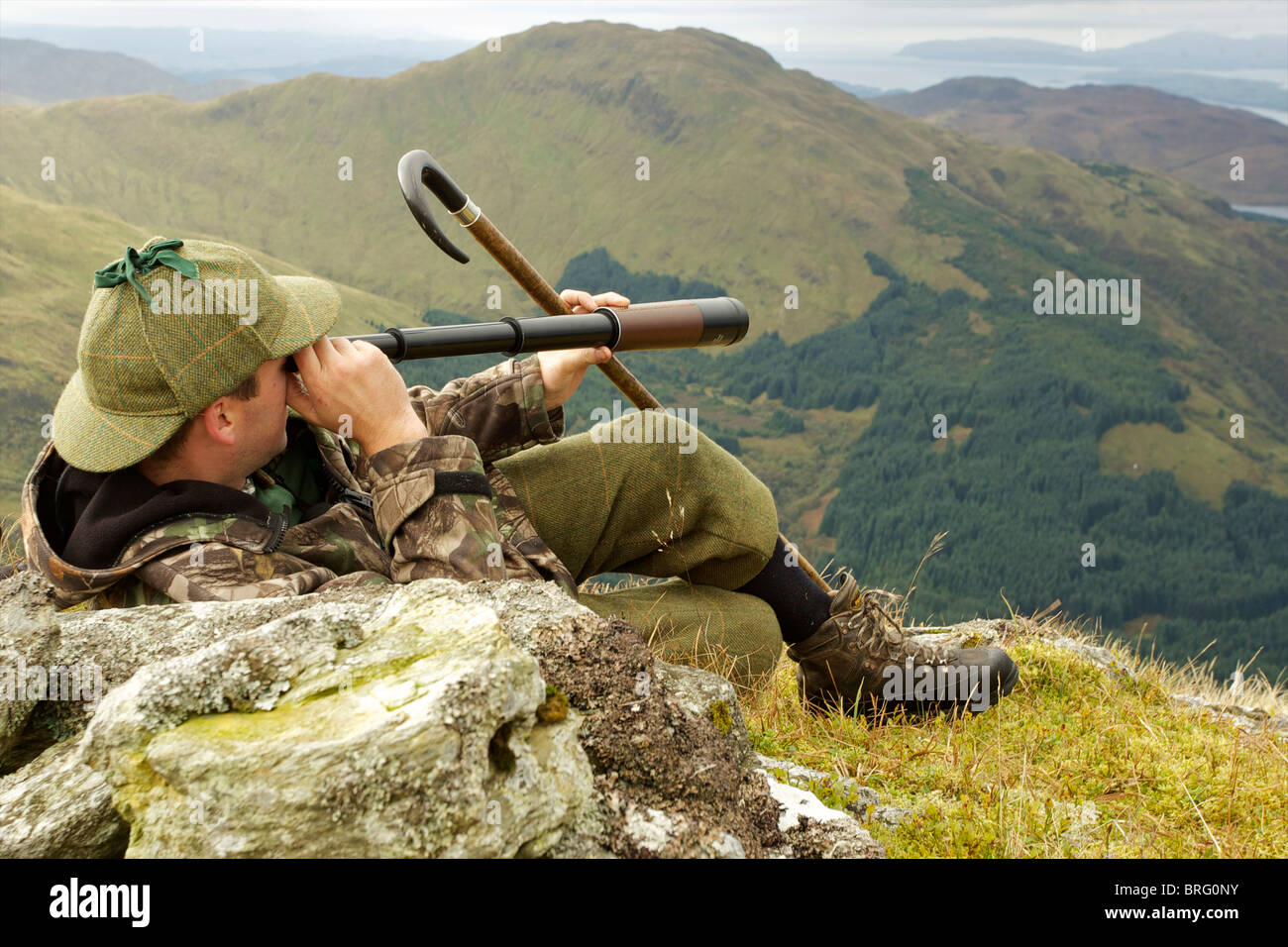 Scottish deer stalker spying for deer using a three draw telescope Stock Photo