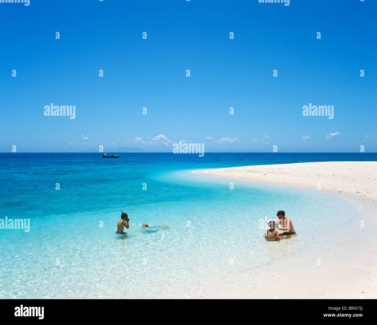 Great Barrier Reef, Australia. Family on a sandbank with a dive boat in the distance, near Cairns, North Queensland, Australia Stock Photo
