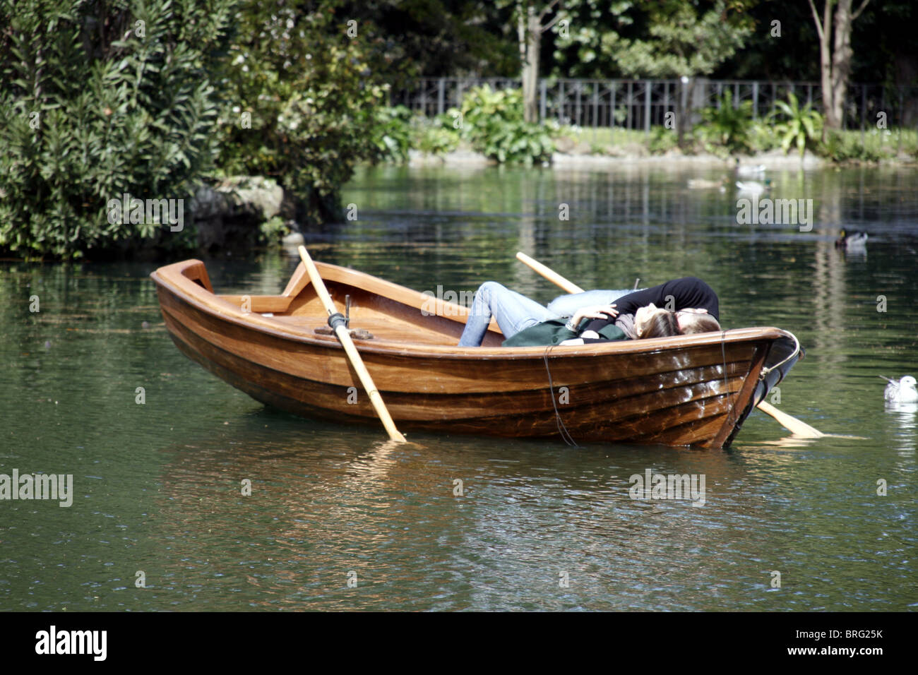 young couple in rowing boat on lake in villa park in rome