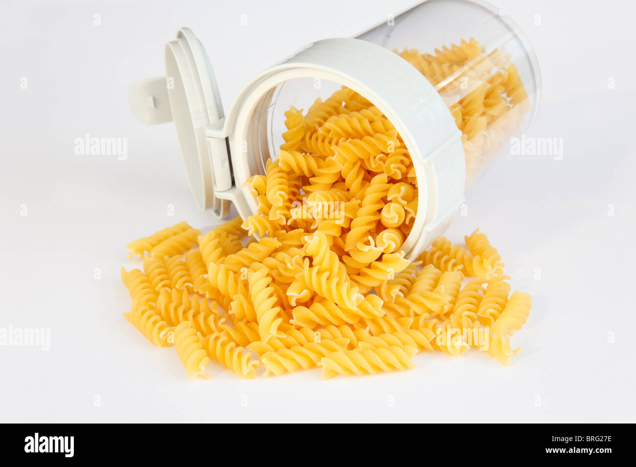 Pile of uncooked Eliche pasta twirls spilling out of a food container open top Stock Photo