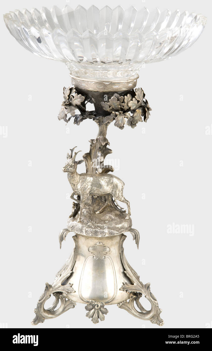A German table centrepiece decoration,circa 1860.A silver table centrepiece with matching insert and a five-candle candelabra with removable bobeches.Each in the shape of a finely made oak trunk with filigree branches and leaves behind,a roe deer in front.Both pieces on bases with embossed line ornamentation and feet of twisted roots.Each is numbered(candelabra '21744',centrepiece,'22263').The centrepiece stamped.The candelabra bears the 12-Loth(.750 silver)hallmark.Height of the centrepiece 46 cm.That of the candelabra 57 cm.Silver weight of th,Additional-Rights-Clearences-Not Available Stock Photo