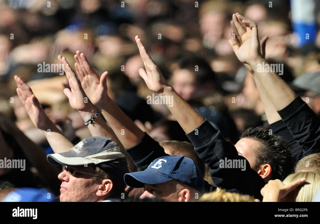 spectators at football match raise their hands in the air in support of their team Stock Photo