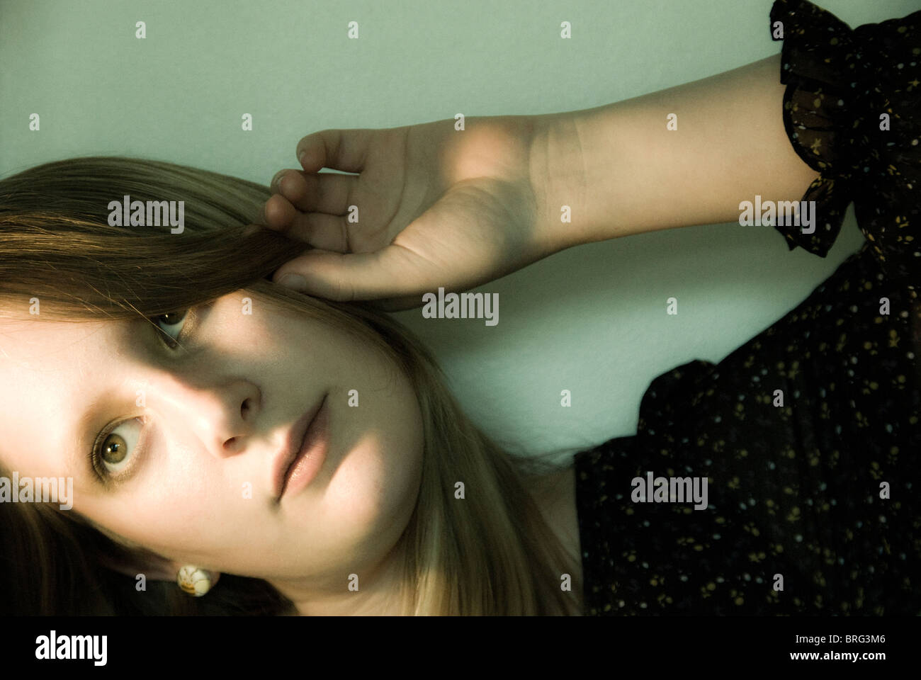 A young woman pulling her hair back from her face Stock Photo - Alamy