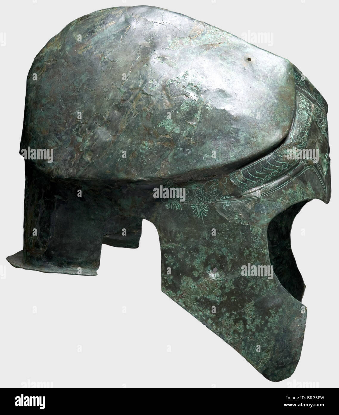 A Chalcidian helmet,5th/4th century B.C.Bronze.Narrow elongated skull with a carinated and crested crown,holes for the plume attachment,large cheek pieces and ear cutouts,and a short flaring neck guard.The forehead has decorative eyebrows in relief and richly chiselled decorative palmettos,serpents' heads,locks of hair,and floral ornamentation.The right cheek piece has a nail hole,presumably from the votive offering of the helmet in a sanctuary.Height 23 cm.Weight 828 g.The metal is distorted,but well-preserved with dark-green patina.The interi,Additional-Rights-Clearences-Not Available Stock Photo