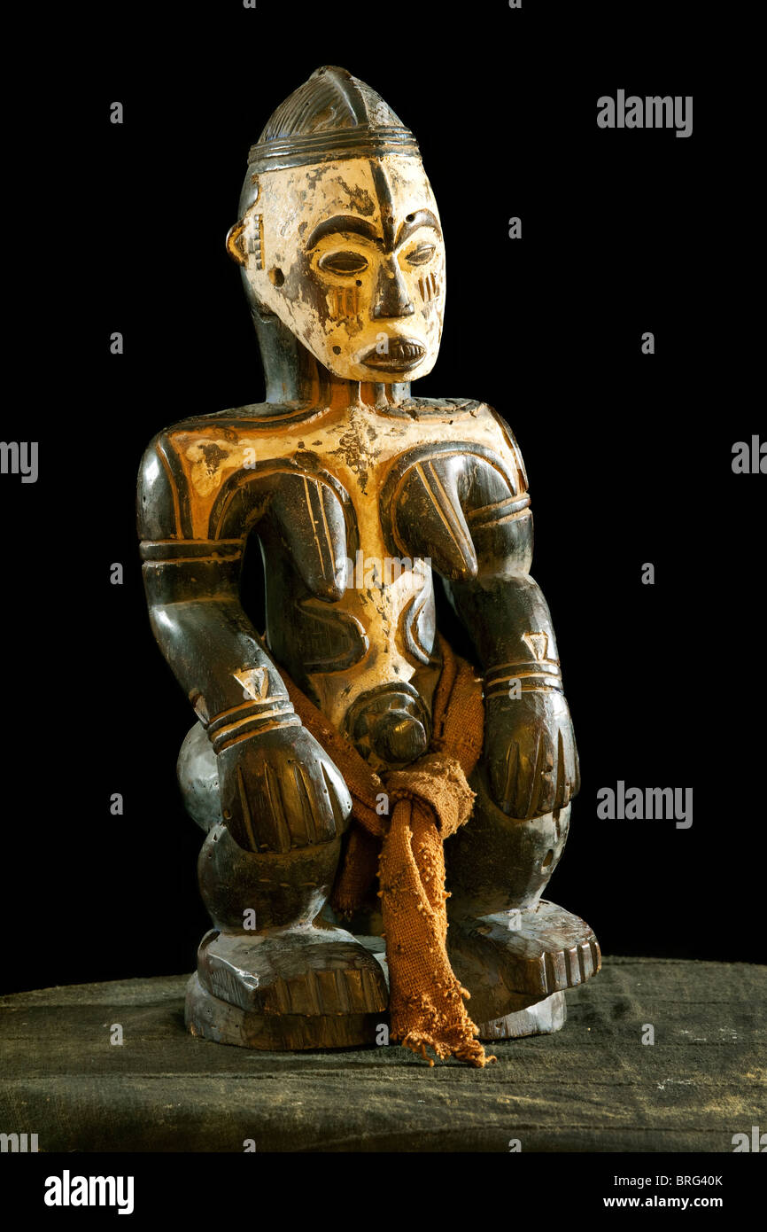African full body wood carving Idol / deity / god. painted white face and body ritualistic. on African cloth, Stock Photo