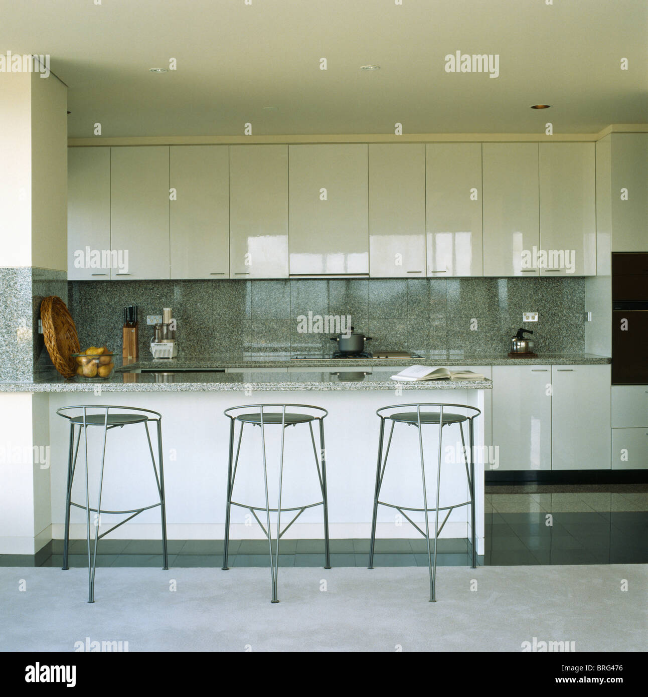 Black metal stools at breakfast bar in modern white kitchen with