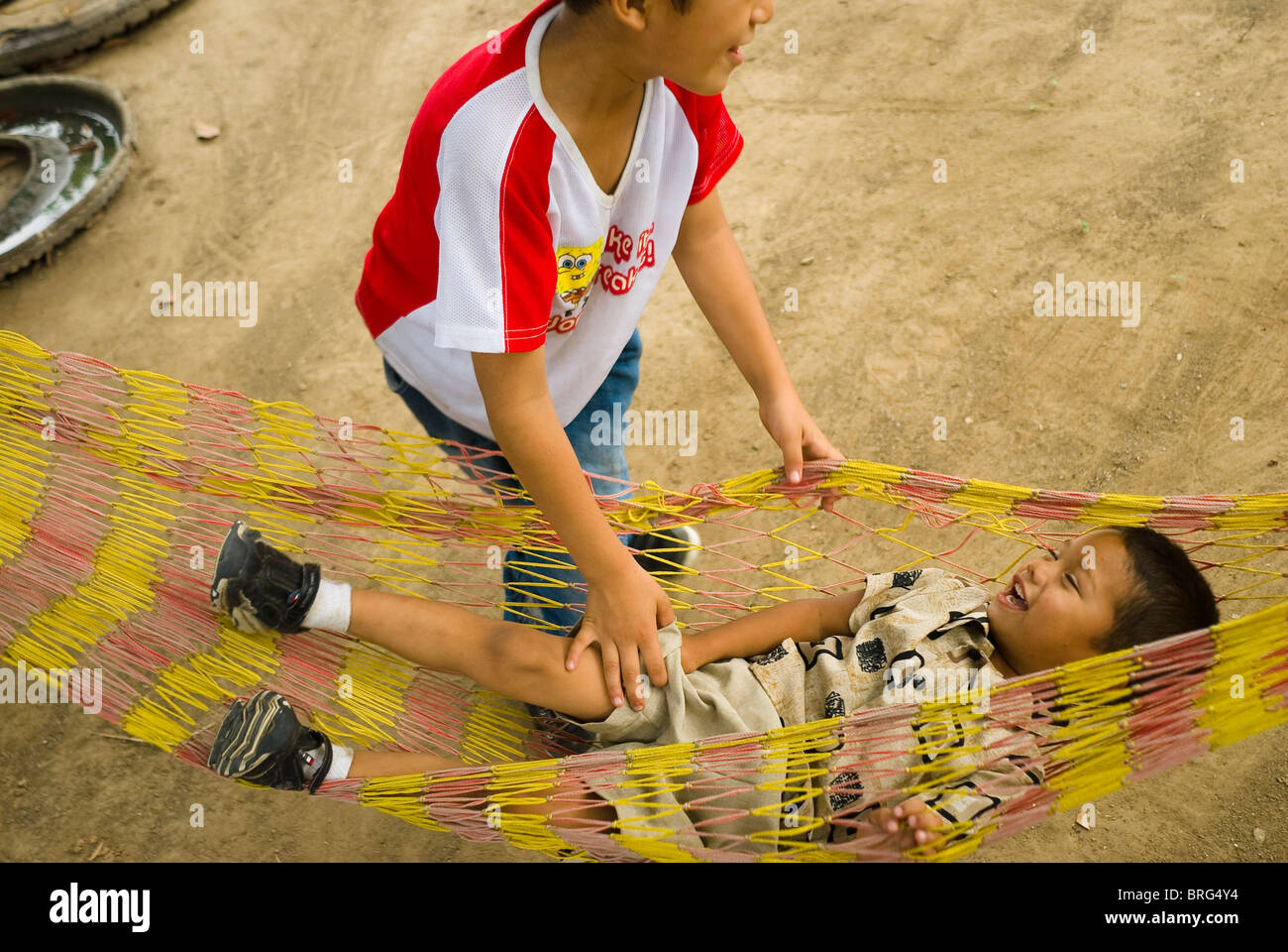 Luis Campos Ordinola plays with brother Angel in a hammock in the yard of the family's home in Tres Valles. Stock Photo