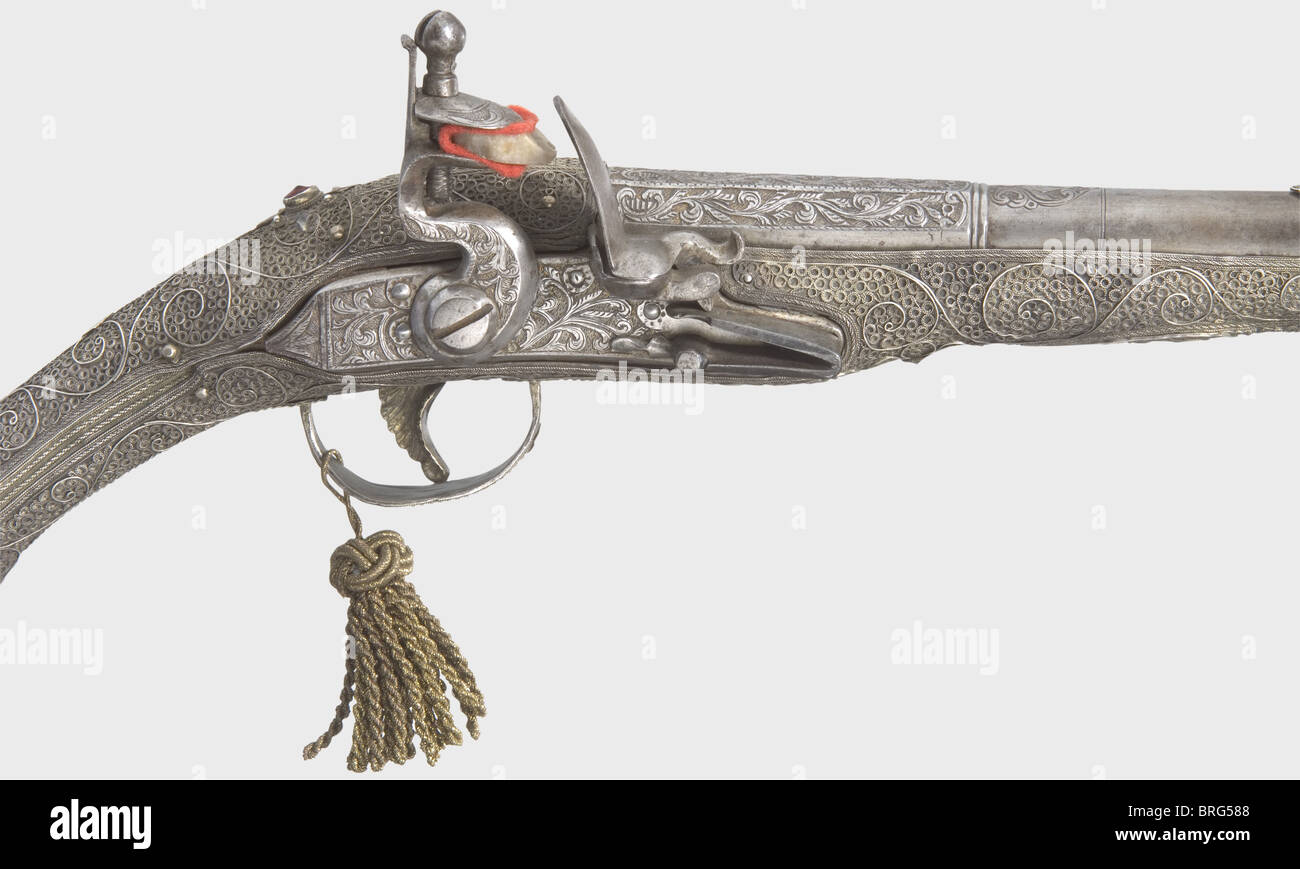 An Ottoman flintlock pistol with a silver filigree stock,19th century Two-stage barrel,octagonal then round after a baluster,with smooth bore in 16.5 mm calibre and chiselled vine designs above the chamber. Iron flintlock cut en suite. The wooden stock is completely covered with fine silver filigree between vines. A glass stone inset behind the tang. Pistol is in fine condition and displays unusually beautiful craftsmanship. Length 41 cm.,historic,historical,19th century,Ottoman Empire,handgun,handheld,firearm,fire arm,gun,fire arms,firearms,guns,Additional-Rights-Clearences-Not Available Stock Photo