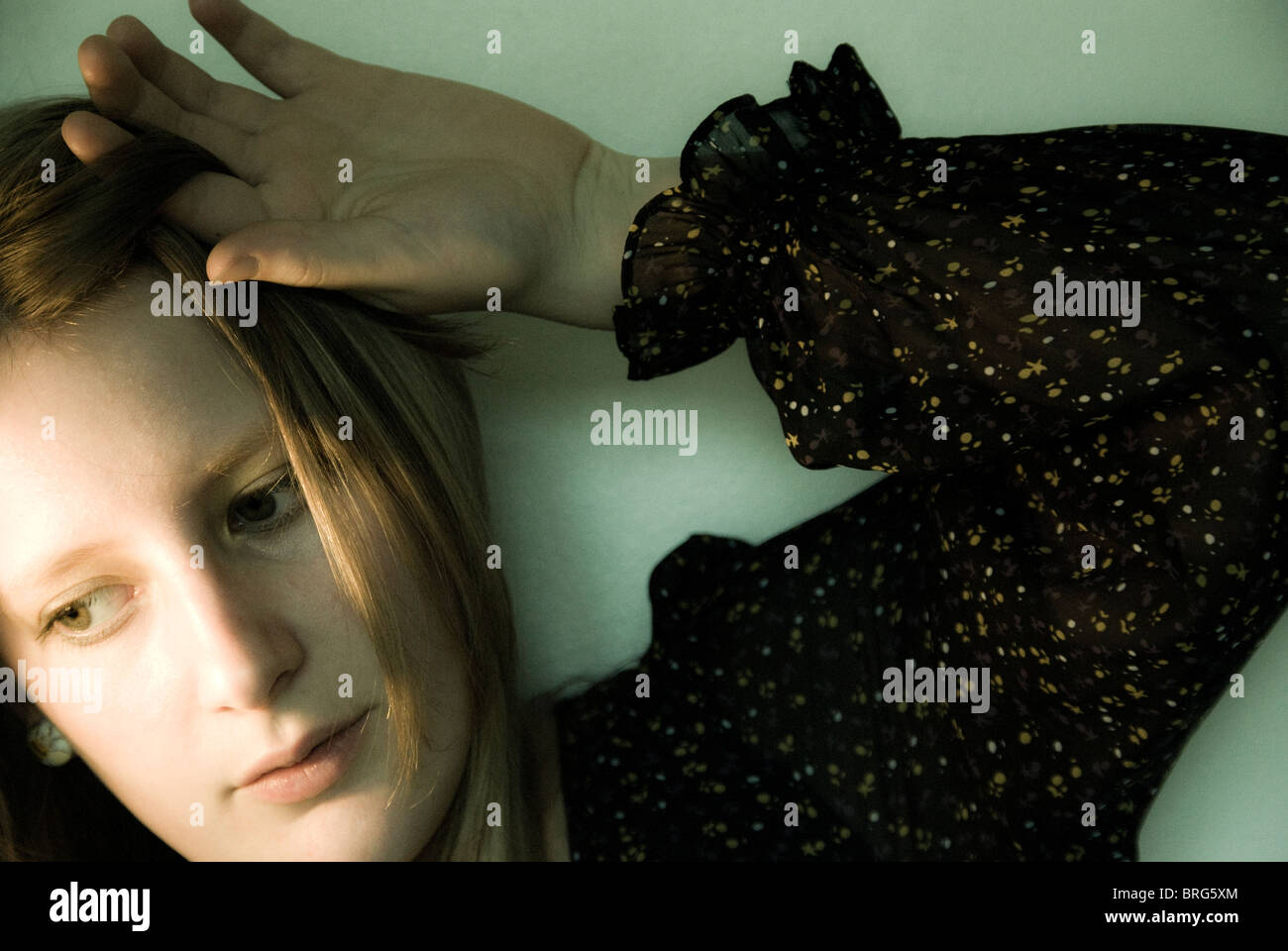 A young blonde woman pulling her hair back from her face Stock Photo ...