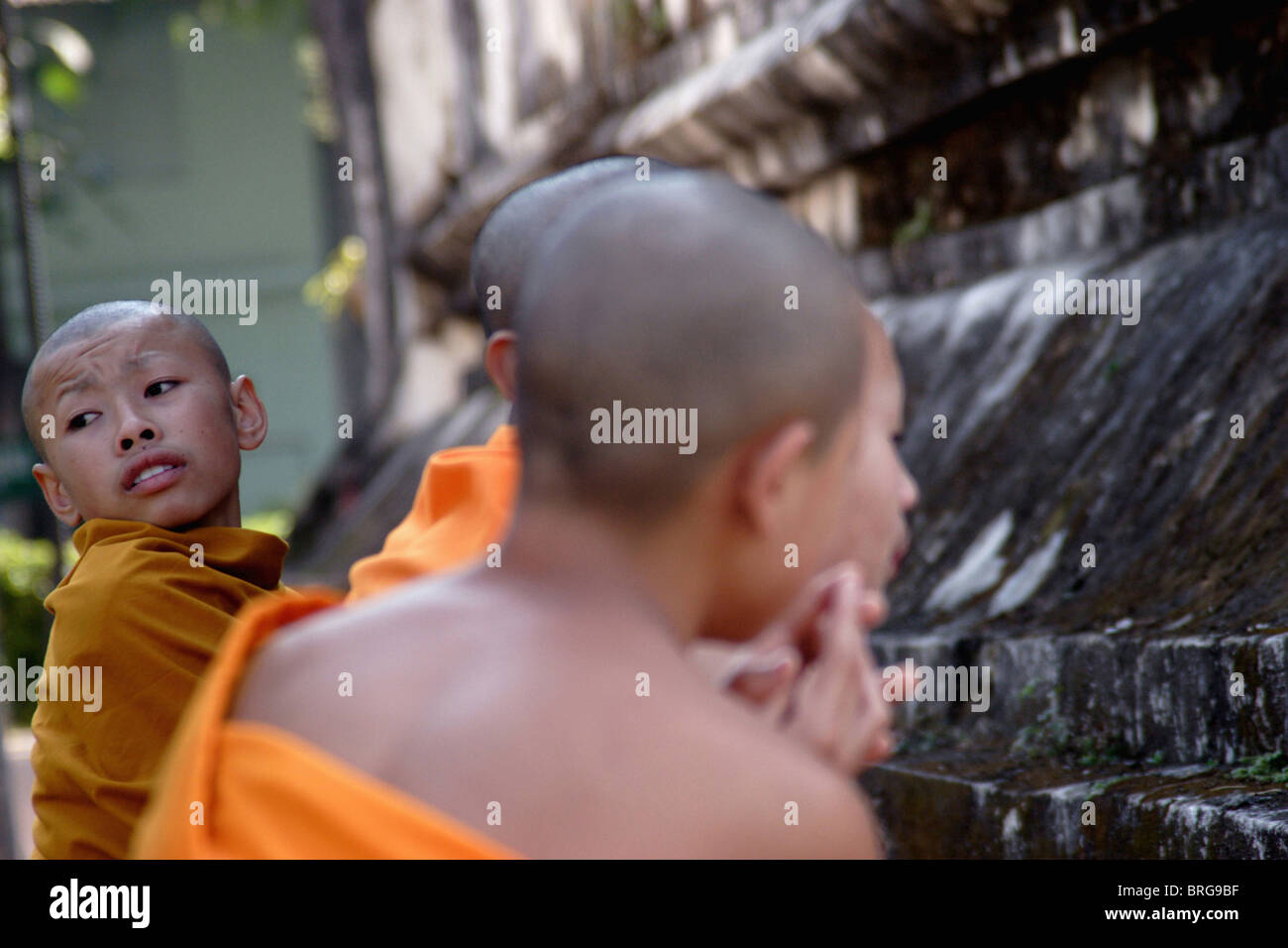 Novice monks pray at the base of a large stupa at historic Wat Hua Kuang in Nan, Thailand. Stock Photo