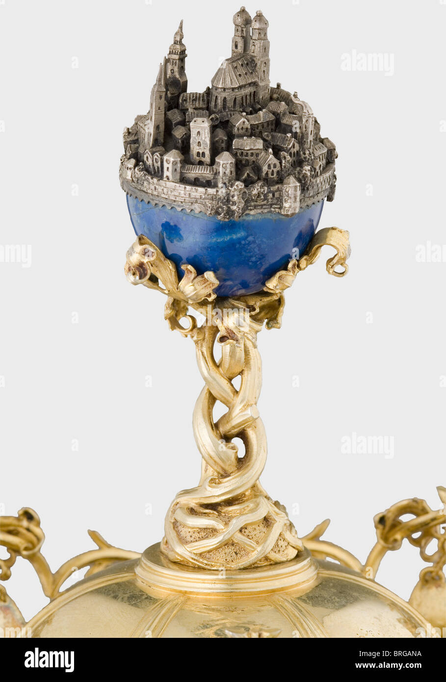 A trophy cup,for the XVth German National Shooting Competition,Munich 1906 A tall,chalice shaped,gilded silver,cup with a lid.The lid bears a lapis lazuli ball supported by roots with a silver miniature of the city of Munich.The rim is surrounded by vine work containing shields displaying shooting symbols and flowers set with star sapphires,carnelians,and agates.The obverse side of the cup displays brewing tools between the initials 'J' and 'S' and the inscriptions 'Ehrengabe für das XV.Deutsche Bundesschießen München 1906'(Prize for the XVth German,Additional-Rights-Clearences-Not Available Stock Photo