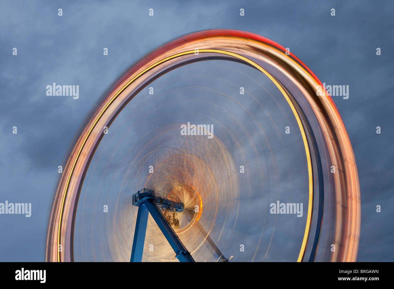 Ferris wheel with motion blur lit up at dusk at the Oktoberfest, Munich ...