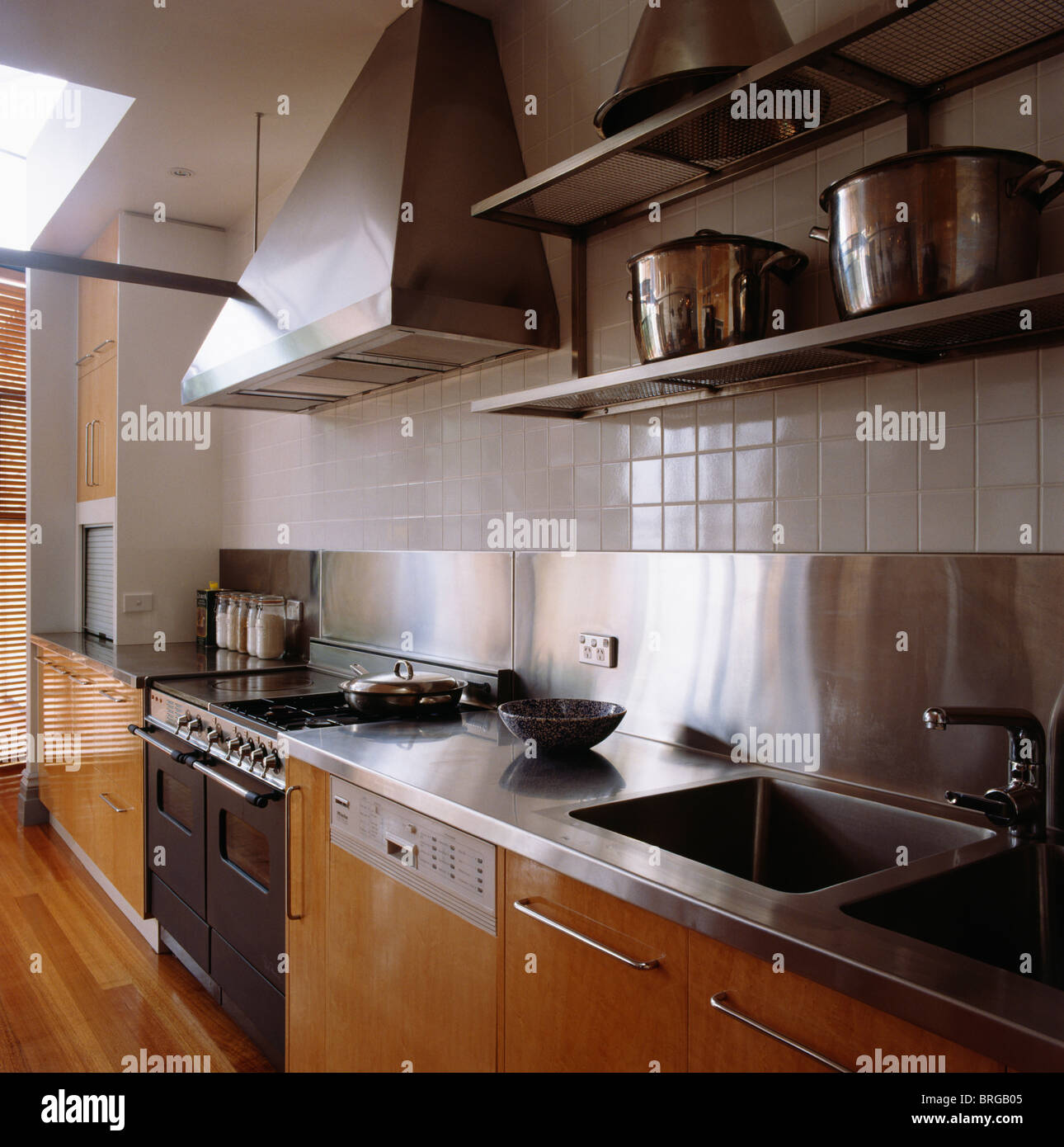 https://c8.alamy.com/comp/BRGB05/pans-on-steel-shelves-on-wall-above-steel-sink-in-fitted-unit-with-BRGB05.jpg